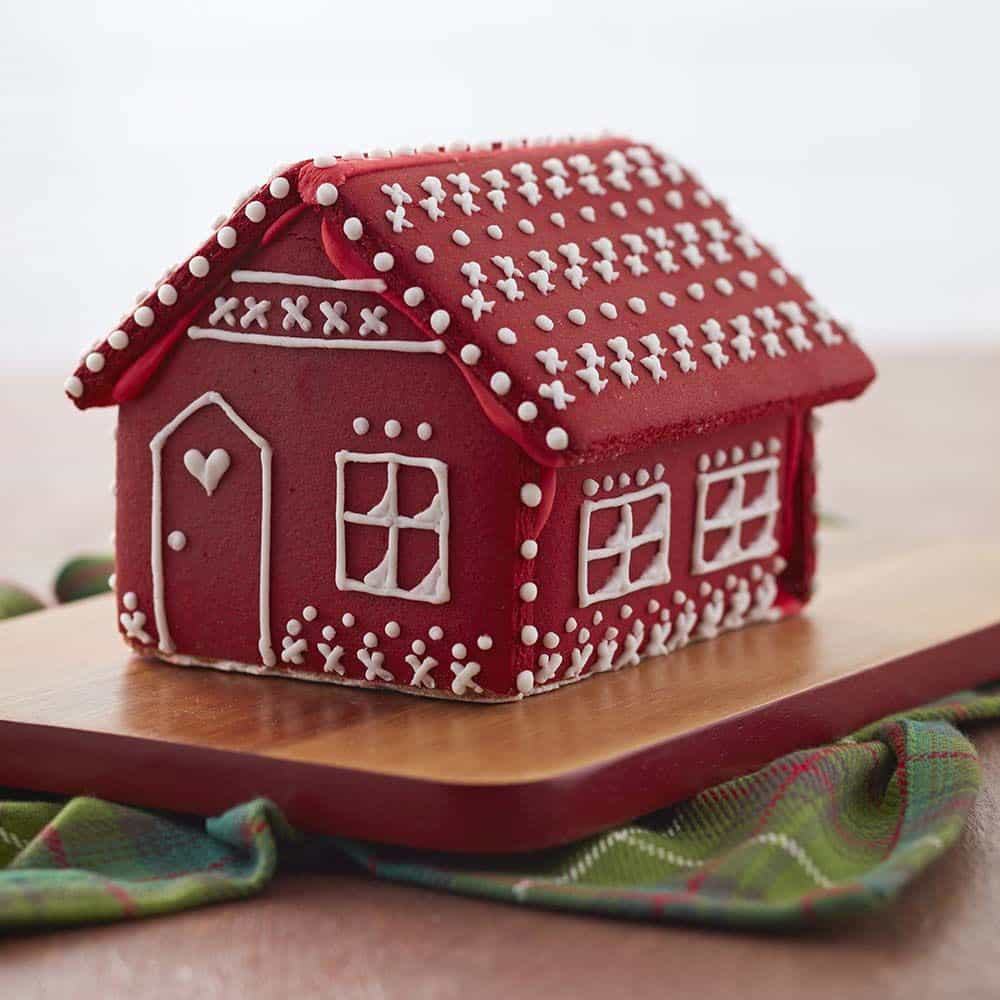 color-mist-gingerbread-house Christmas Red gingerbread house with white details on the roof and walls. Door has a little white heart with a window next to it.