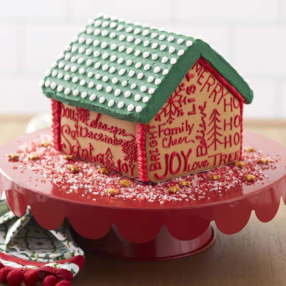 color-right-gingerbread-house Gingerbread house with a green roof with white candy dots and on the walls of the house, Christmas words written in red. Words such as Joy, Family Cheer, Ho Ho Ho