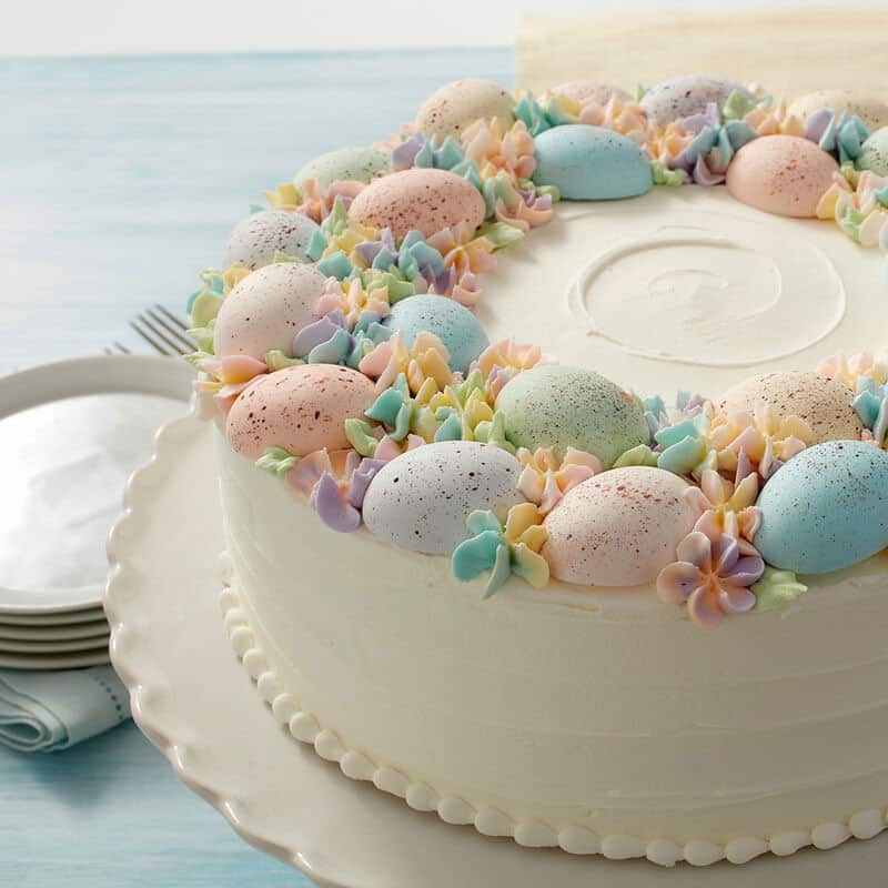 Easter-Egg-Cake Cake topped with chocolate speckled pastel eggs and piped flowers