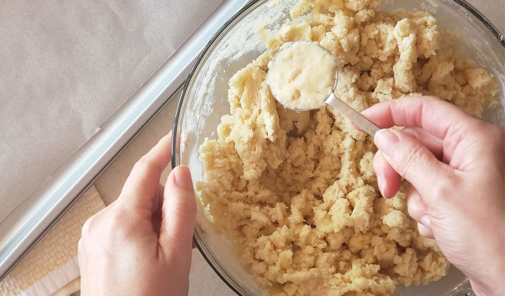 Sugar Cookie Step 6- Scoop cookie dough making sugar cookies step 6 scooping cookie dough out of bowl
