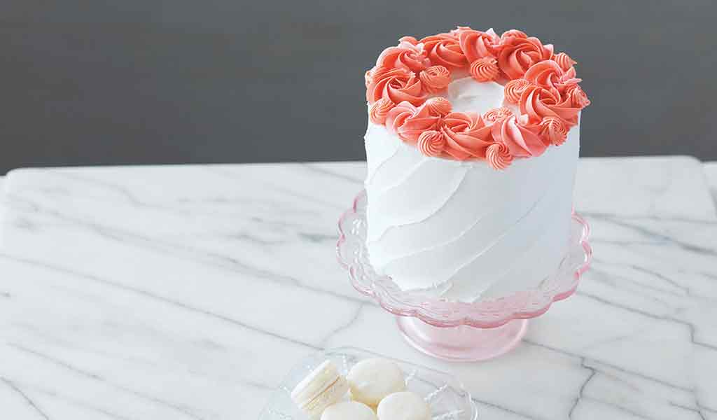 vanilla buttercream cake decorated with coral buttercream rosettes