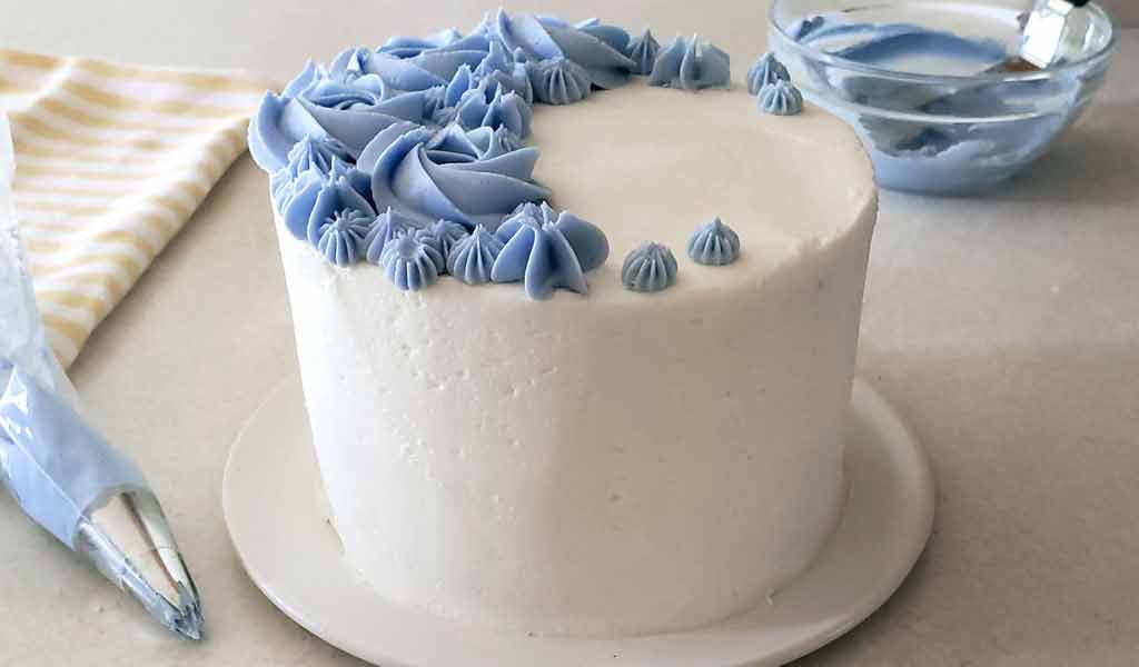 cake frosted with a crusting buttercream frosting and decorated with blue buttercream flowers