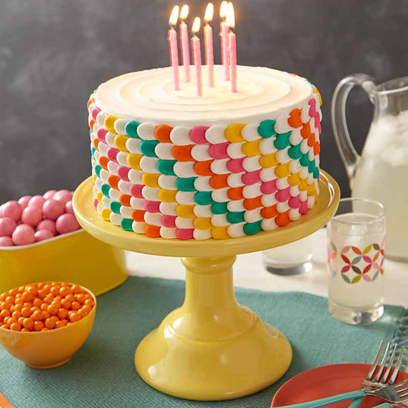 pulled-dot-cake chocolate cake decorated with pink and purple rosettes piped with star tip
